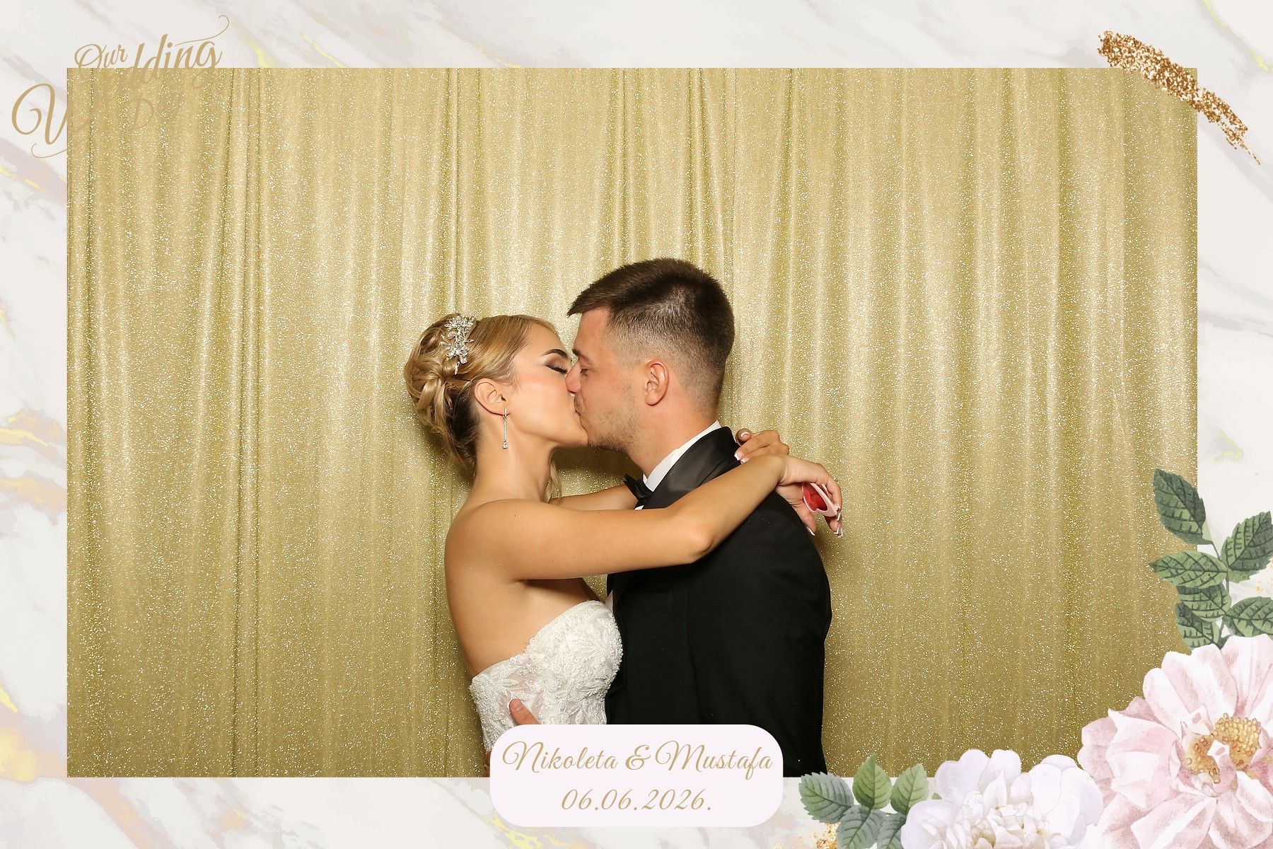 The newlyweds in front of the gold backdrop at their wedding